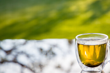 Cup with herbal tea on the table, gazebo in the backyard