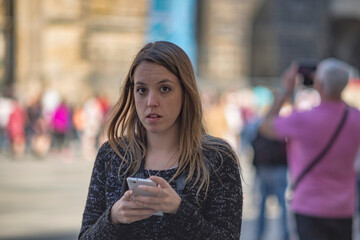 Young girl on vacation, she's in the square chatting with her mobile