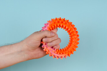 A hand clutching a red rubber expansion band against a blue back