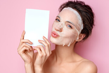 Smiling woman holds cosmetic packaging of facial mask and send air kiss. Photo of attractive woman...