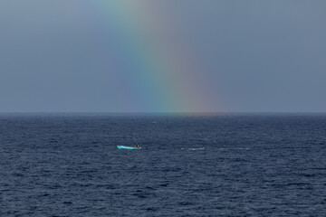 Arc en ciel sur pêcheur seul en mer