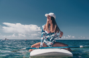 Healthy happy fit woman in bikini relaxing on a sup surfboard, floating on the clear turquoise sea...