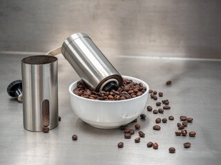 Roasted coffee beans with separated manual grinder on table