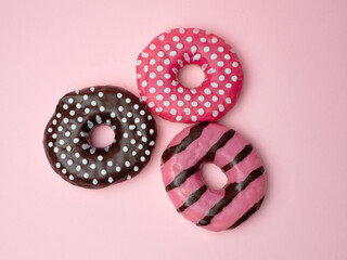 Strawbery and chocolate donut with sprinkles on pink background