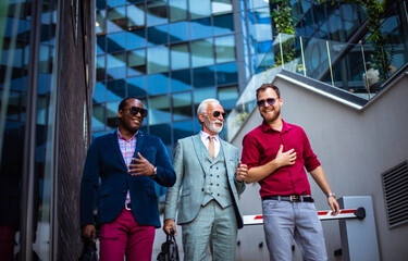 Obraz premium Three happy business men walking and talking outside.