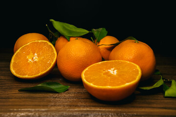 oranges and orange slices on a wooden board on a black background