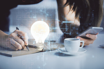 Double exposure of light bulb hologram and woman holding and using a mobile device. Idea concept.