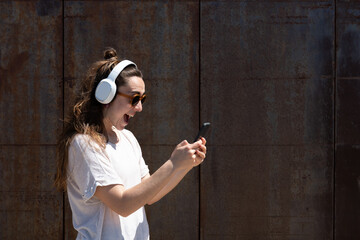 Happy woman receiving good news on her phone isolated on oxidized metallic wall.