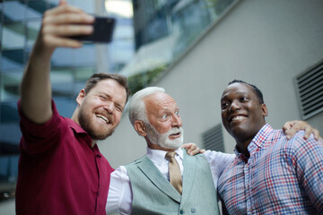 Funny photo.  Three business men standing outside and using mobile phone. Focus is on background.