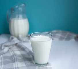 A glass of fresh milk and a jug in the background on a blue background. Healthy and delicious breakfast. Milk Day. copy space for text. selective focus