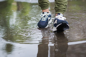 Legs in a puddle. Walk through the puddles. Rain. footwear. Sneakers.