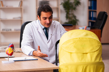 Young male doctor looking after new born in the clinic