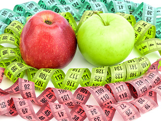 Bright colored measuring tapes, twisted in a spiral around a red and green apples, isolated on a white background. Fitness, diet, weight loss concept. Weight loss.