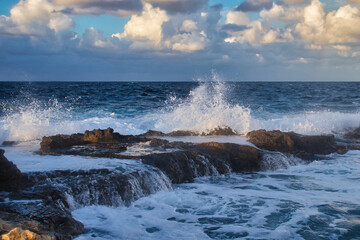 Water splashing and running over rocks in the ocean at Qawra, Malta on a fall evening.