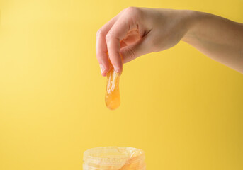 Fototapeta premium Hand with sugar wax piece from jar on yellow
