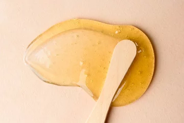 Fotobehang Liquid sugar wax smear with spatula on beige background © molenira