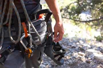 Climbing equipment on a male climber: rock shoes, rope, quickdraw, safety device, harness. Sports...