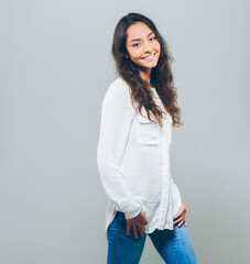 Beautiful brunette woman with long hair in white shirt and jeanse over gray background happy smile teeth