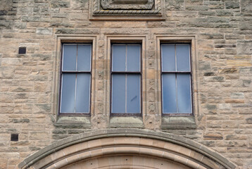 Three Identical Windows in Wall of Old Stone Building above Arched Entrance 