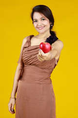 Senior cute Asian woman holding and showing apple, studio shot on yellow background.