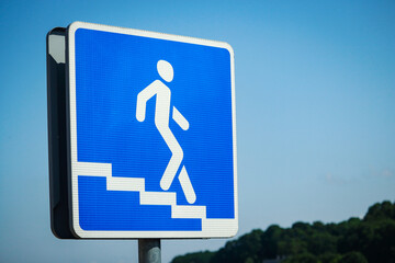 Underground crossing sign walking down the stairs man on blue sky background