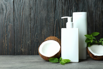 Shower gels and coconut against wooden background