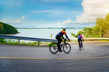 Empty space. Cyclist male in helmet cycle outdoor in summer. The activity of bicyclist bike speed race action on the hill road, above is sea and sky in background. Horizontal photo of biker.