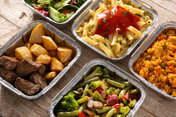 Take away healthy food in foil boxes on wooden table	