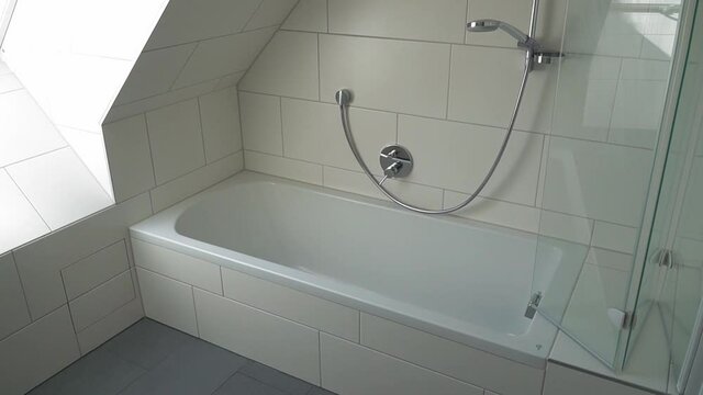 Bathtub in a small and empty bathroom with a window.