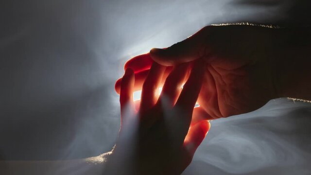 Giving helping hand, hope and support each other concept. Woman hand reaches out and touches man hand receiving help, support and protection. Backlight, rays of light break through fingers and light