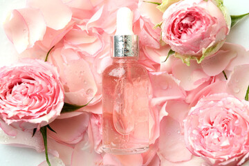 Bottle with rose essential oil on rose petals background
