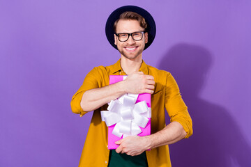 Photo of charming positive happy young man hold hands hug gift box isolated on purple color background