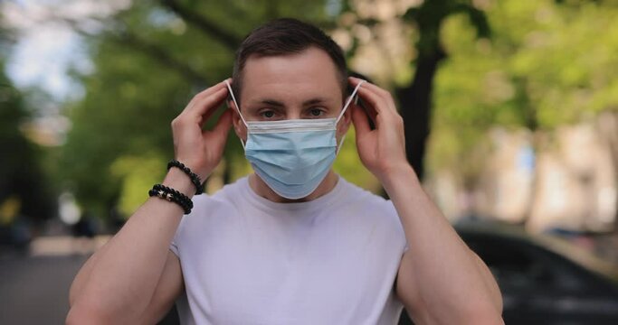 Man putting on surgical mask in a city, coronavirus pandemic