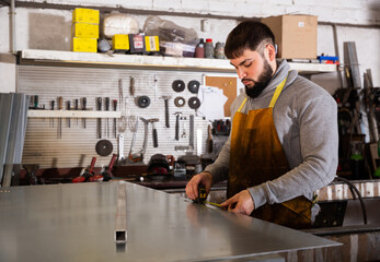 Skilled man worker working with measuring tape in workshop