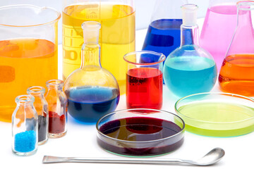 Laboratory glassware with various colored liquids in chemistry laboratory. Volumetric laboratory glassware over white background