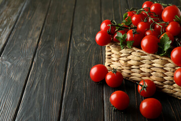 Wicker basket with cherry tomato on wooden background