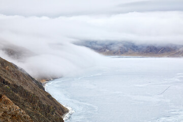 thick fog descends from the mountains to the water