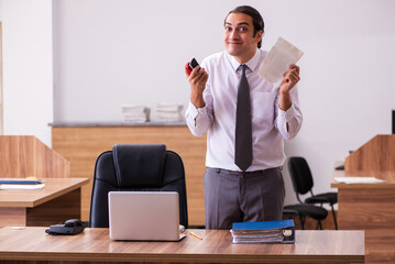 Young male employee stapling paper in the office