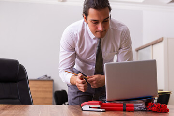 Young male employee with dynamite in the office