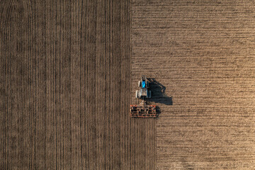 Top view of a tractor harrowing soil on an agriculture field. Acricultural tillage or land preparation.