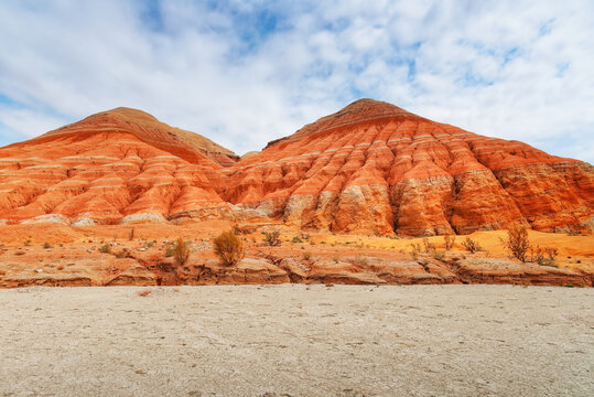 Hills of ancient multi-colored sediments, red yellow and white clay, erosion, desert vegetation. View of the Altyn-Emel park in Kazakhstan