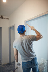 Young adult man painting on a DIY budget renovation of his new home apartment.