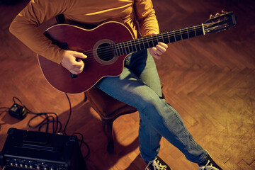 Male musician playing acoustic guitar on the amplifier in retro vintage room. - obrazy, fototapety, plakaty