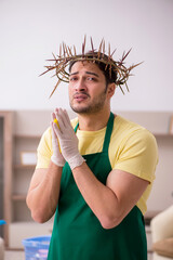 Young male contractor wearing prickly wreath on head cleaning th