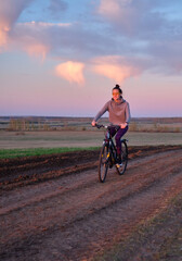 Summer, field, sunset, beautiful sky. The girl rides a bike.