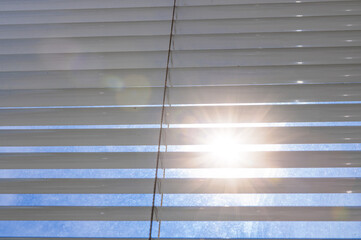 Sun shining through window blinds. The bright sun breaks through the ajar blinds.