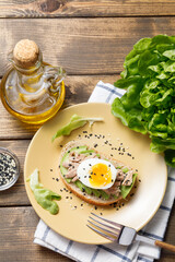 Avocado, canned tuna and boiled egg toast on wooden table background. Healthy food, avocado open sandwich for breakfast or lunch. Top view, flat lay