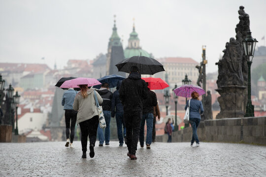People walking with umbrellas on Charles bridge
