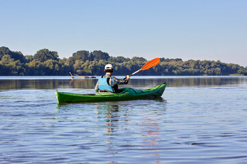 Woman kayaking in green kayak on the danube river at the morning