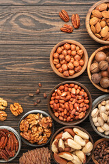 Nuts in bowls. Walnuts, pistachios, pecans, macadamia, almonds and other. Healthy food snacks mix on wooden background, top view